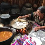 Mayan woman preparing the corn tortillas and traditional stew called pepian.