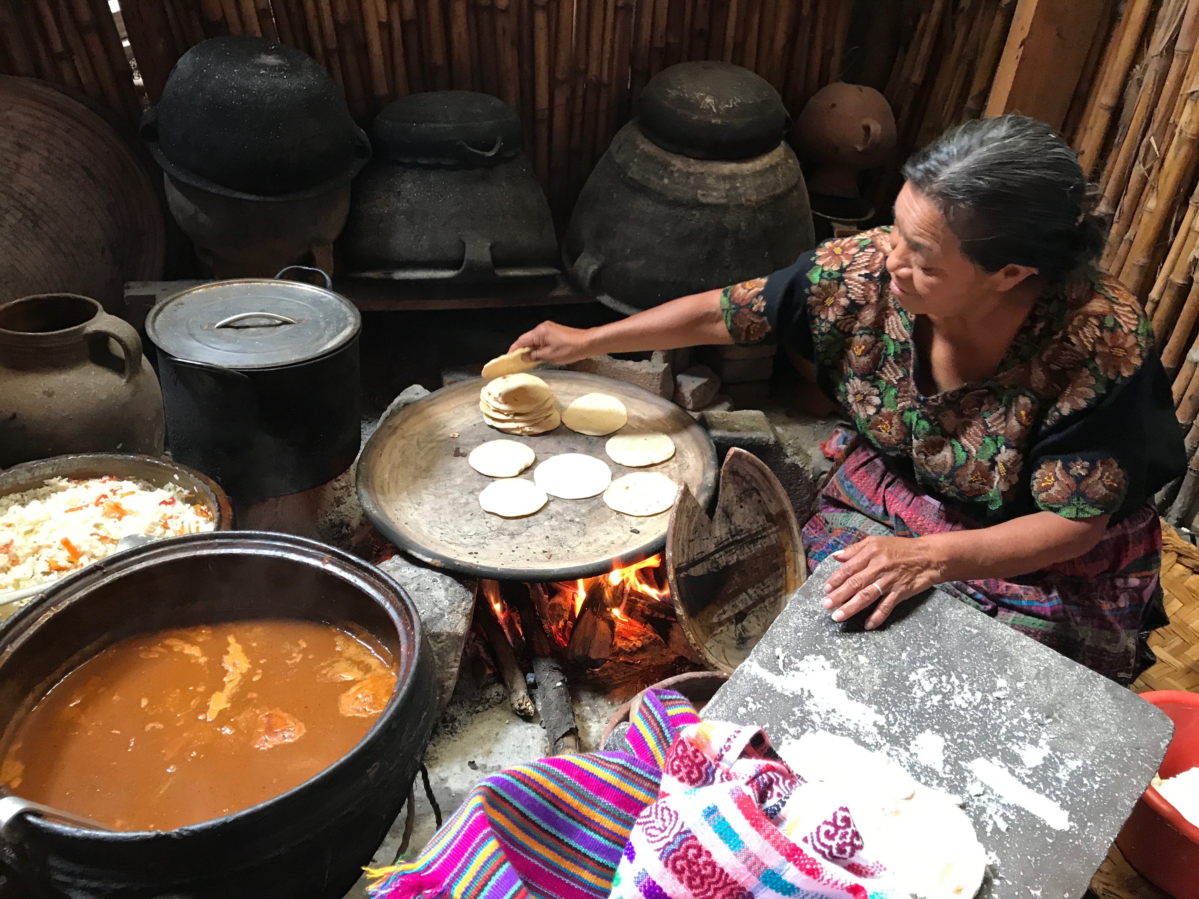 Mayan woman preparing the corn tortillas and traditional stew called pepian.