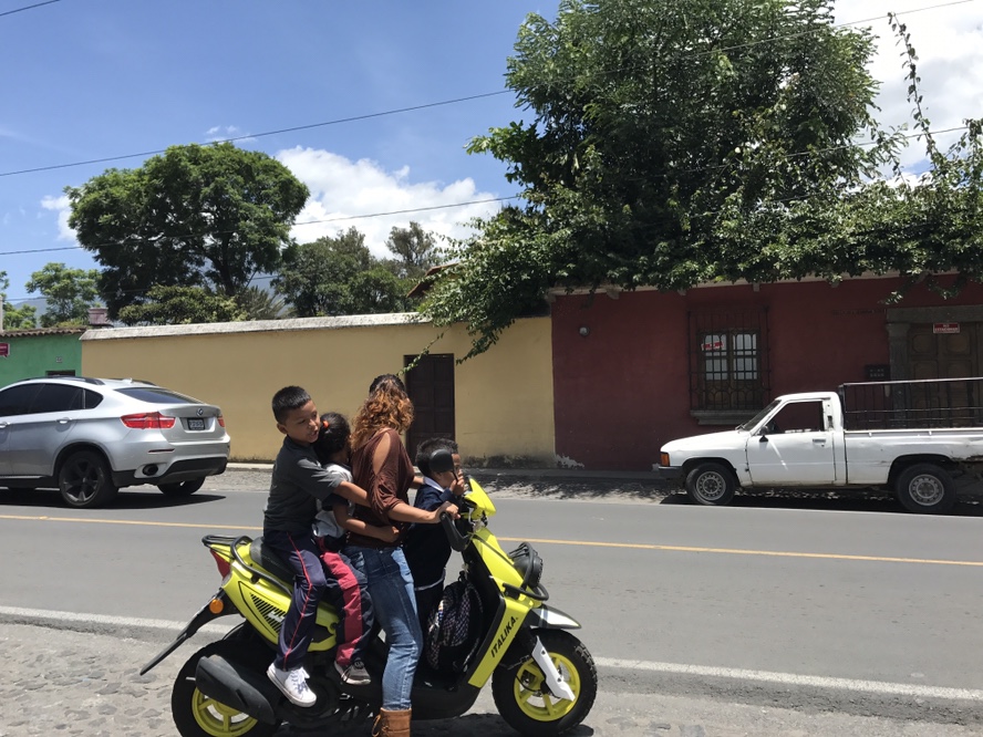 Mother rides motor scooter with children on back in Guatemala